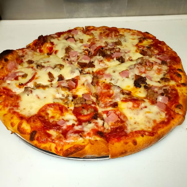 A whole Dough Boys Pizzeria meat lover's pizza, topped with pepperoni, ham, and sausage.