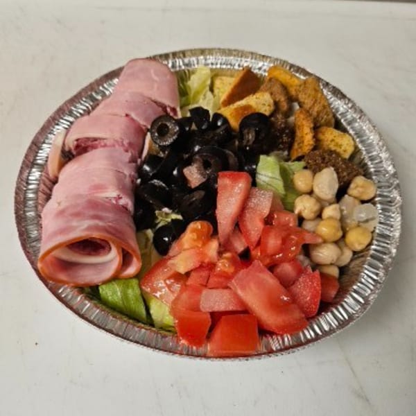 A Dough Boys Pizzeria salad with ham, black olives, tomatoes, chickpeas, and croutons in a foil container.
